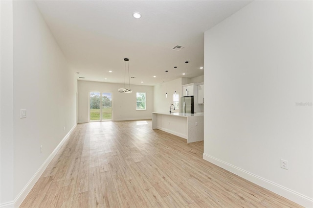 unfurnished living room featuring sink and light wood-type flooring