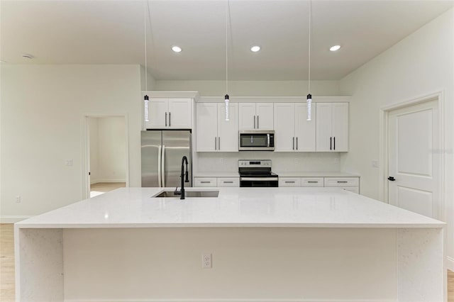 kitchen with decorative light fixtures, sink, stainless steel appliances, and a kitchen island with sink