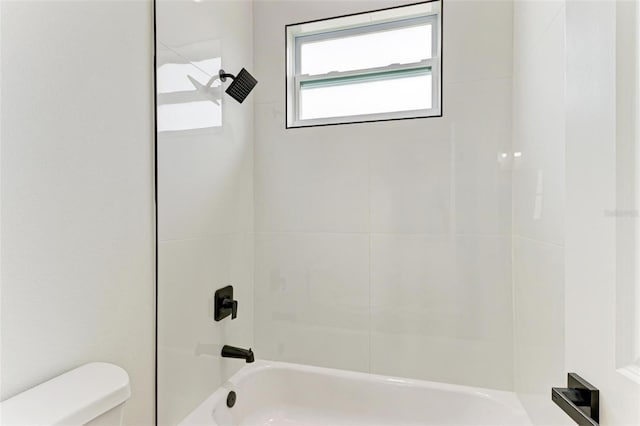 bathroom featuring tiled shower / bath combo and toilet