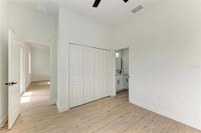 unfurnished bedroom featuring connected bathroom, ceiling fan, a closet, and light hardwood / wood-style flooring