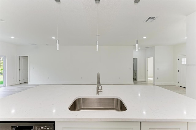 kitchen featuring pendant lighting, light stone counters, a kitchen island with sink, and sink