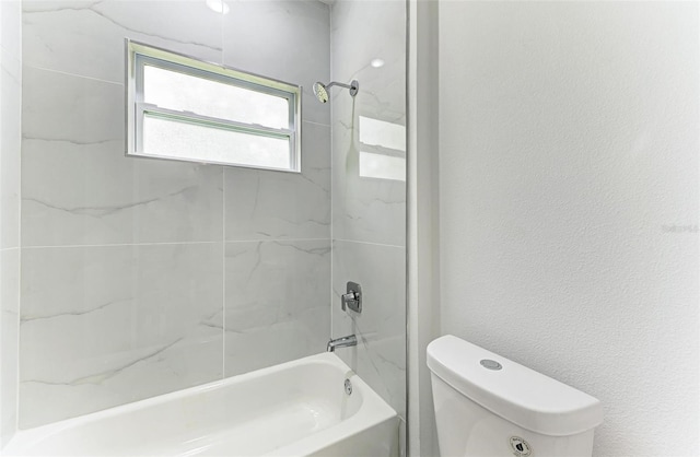 bathroom featuring toilet and tiled shower / bath