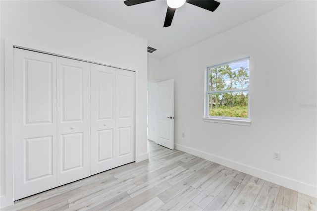 unfurnished bedroom with ceiling fan, light hardwood / wood-style flooring, and a closet