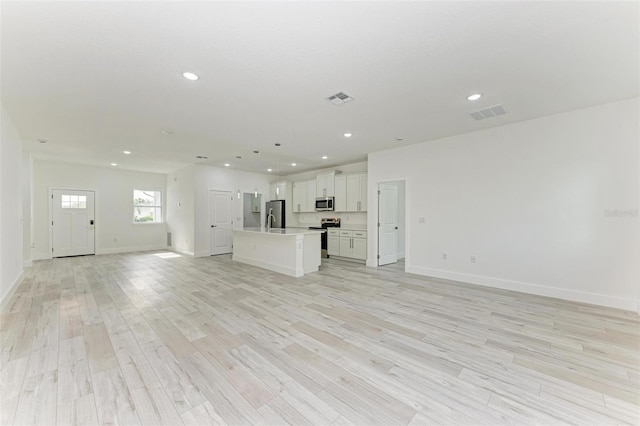 unfurnished living room with sink and light hardwood / wood-style floors