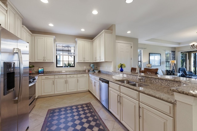 kitchen featuring kitchen peninsula, appliances with stainless steel finishes, light tile patterned flooring, light stone counters, and sink