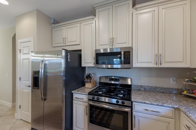 kitchen with light tile patterned floors, stainless steel appliances, and light stone counters