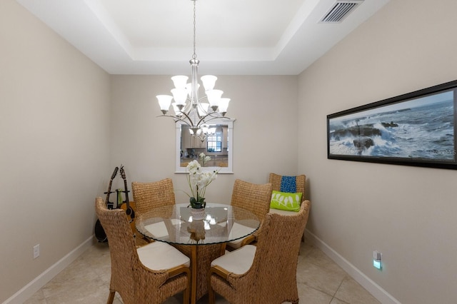 dining area with light tile patterned floors, an inviting chandelier, and a tray ceiling