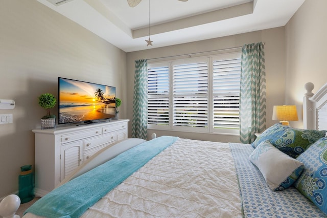 bedroom with ceiling fan and a tray ceiling