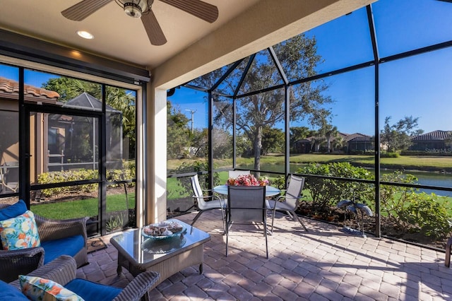 sunroom / solarium with ceiling fan and a water view