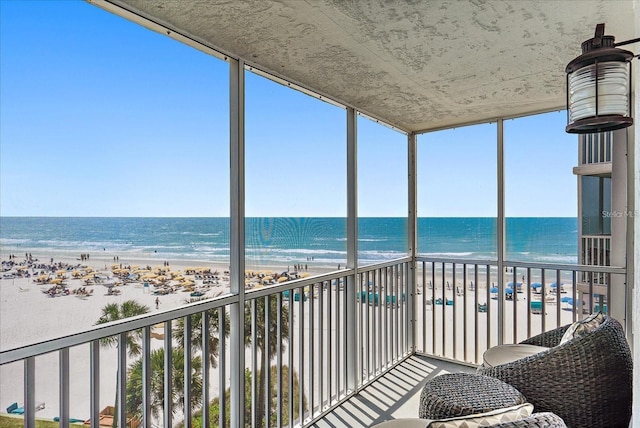 sunroom featuring a view of the beach, a water view, and plenty of natural light