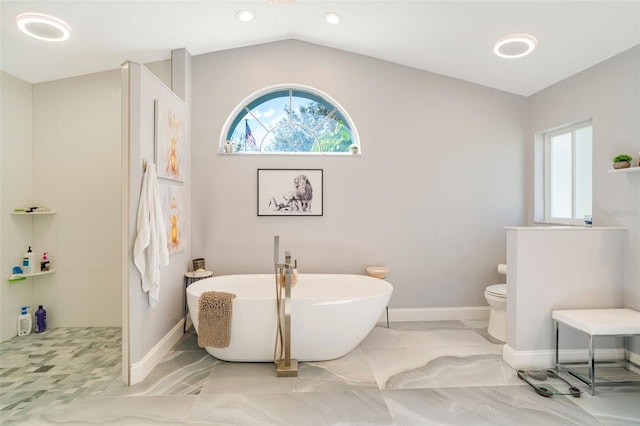 bathroom featuring a tub to relax in, lofted ceiling, and toilet