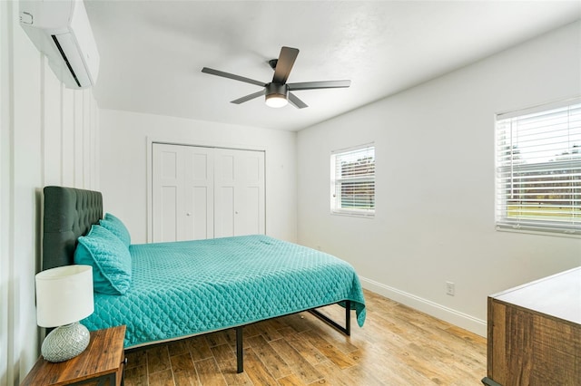 bedroom with a closet, hardwood / wood-style flooring, an AC wall unit, and ceiling fan