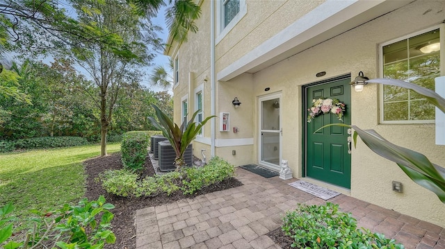 property entrance with cooling unit and a lawn