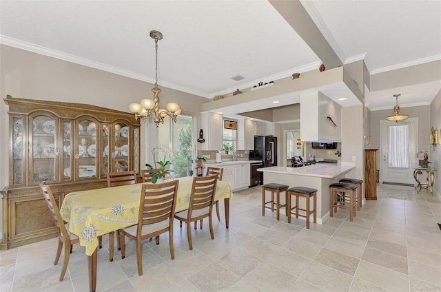 dining room with sink, ornamental molding, and a notable chandelier