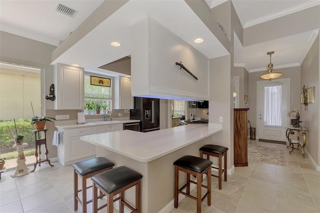 kitchen with white cabinets, a breakfast bar, high end black fridge, and kitchen peninsula