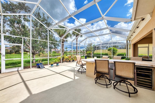 view of patio / terrace with glass enclosure, a bar, and beverage cooler