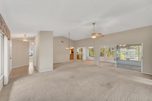 unfurnished living room with ceiling fan with notable chandelier, light colored carpet, vaulted ceiling, and plenty of natural light