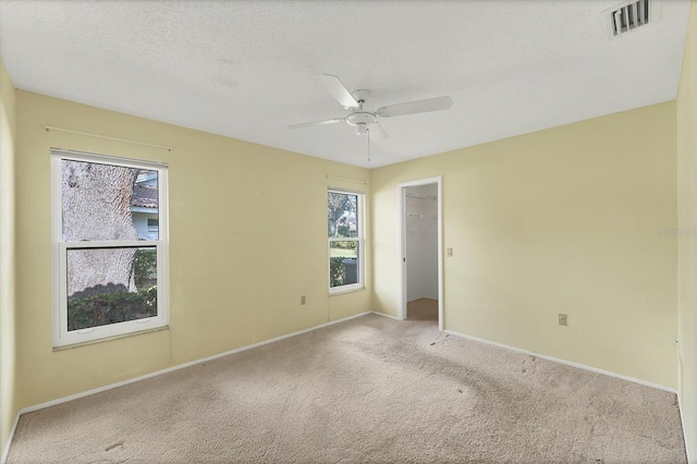 carpeted spare room featuring a textured ceiling and ceiling fan