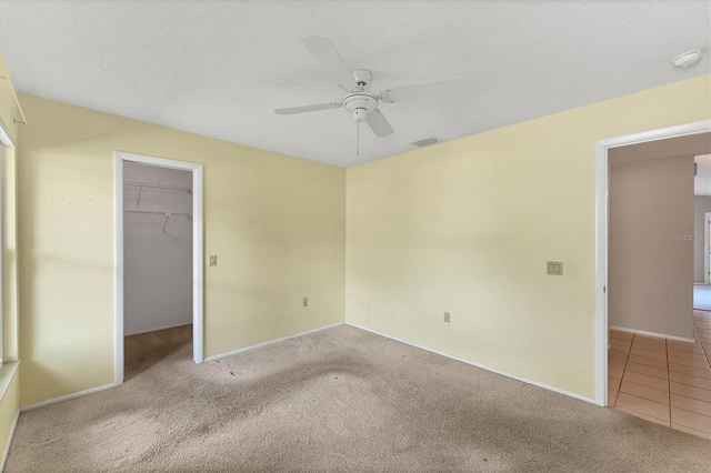 empty room featuring a textured ceiling, light colored carpet, and ceiling fan