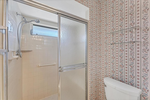 bathroom featuring toilet and a shower with door