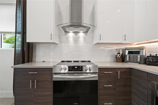 kitchen with white cabinets, backsplash, wall chimney range hood, and electric stove