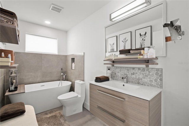 bathroom featuring vanity, a tub to relax in, and toilet