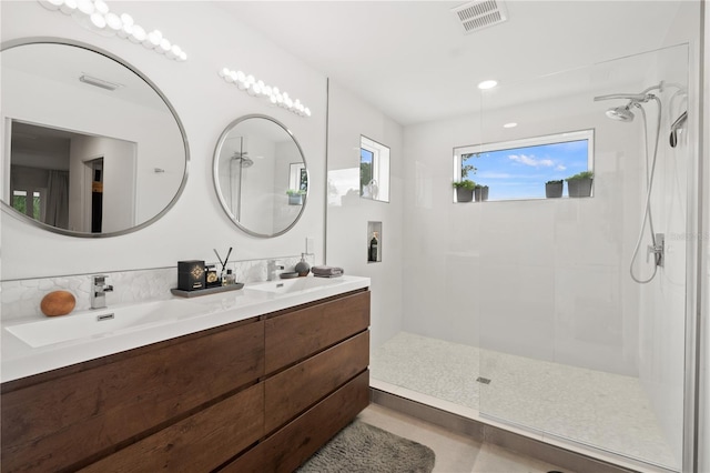 bathroom featuring tile patterned flooring, vanity, and a tile shower