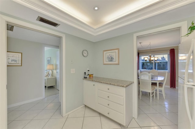 kitchen with white cabinets, white refrigerator, crown molding, light tile patterned floors, and a tray ceiling