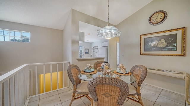 tiled dining room featuring a chandelier and vaulted ceiling