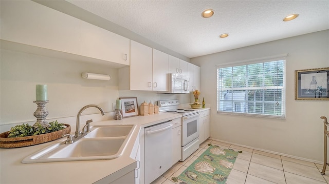 kitchen with white appliances, a textured ceiling, sink, light tile patterned floors, and white cabinetry