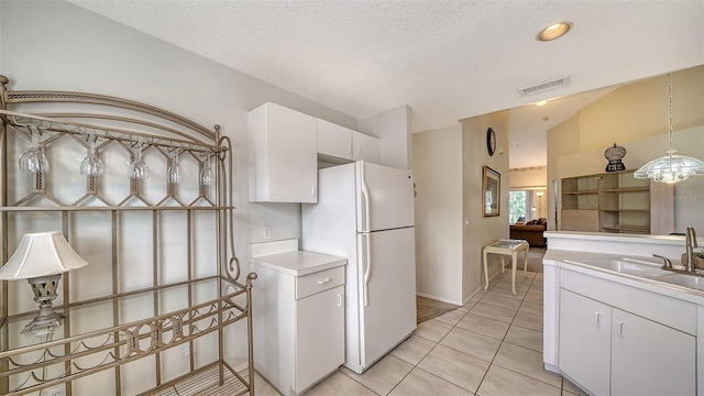 kitchen featuring white cabinetry, sink, white refrigerator, pendant lighting, and light tile patterned floors