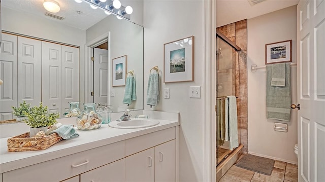 bathroom featuring toilet, vanity, a textured ceiling, and walk in shower