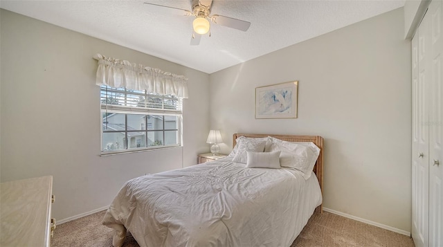 bedroom featuring a textured ceiling, light colored carpet, a closet, and ceiling fan