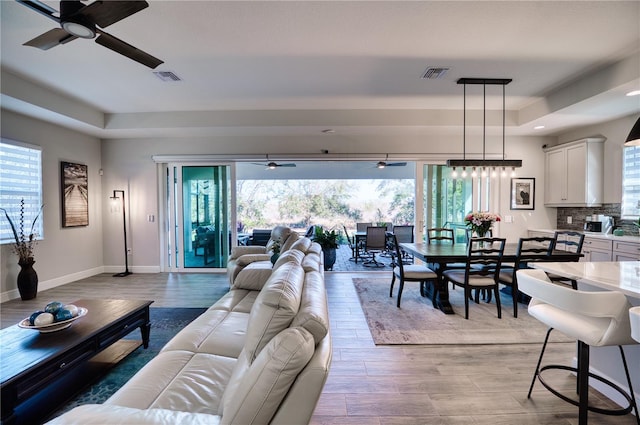 living room with plenty of natural light, a tray ceiling, and light hardwood / wood-style flooring