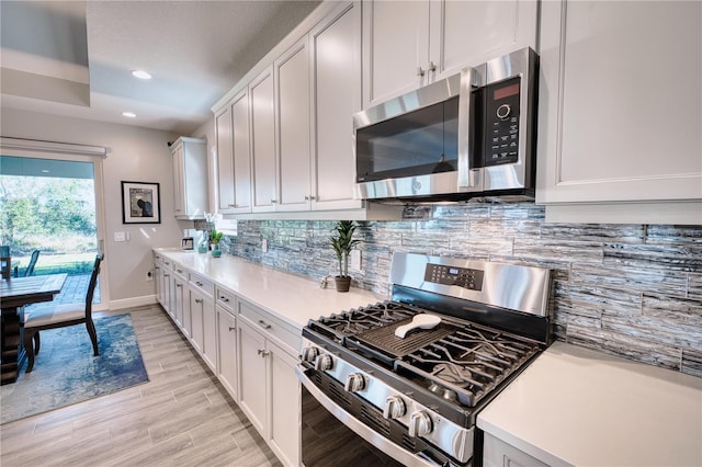 kitchen with decorative backsplash, white cabinetry, and appliances with stainless steel finishes