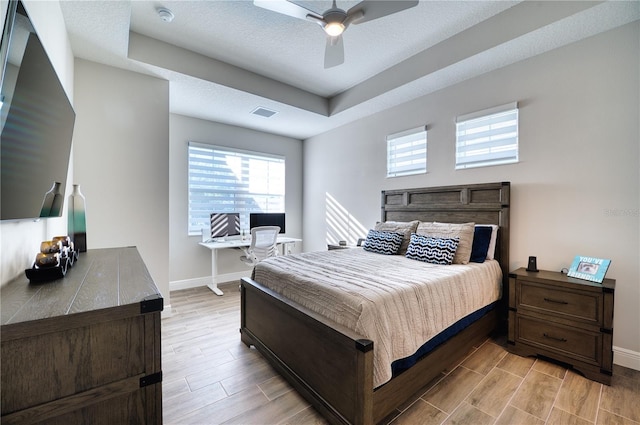 bedroom featuring ceiling fan and a raised ceiling