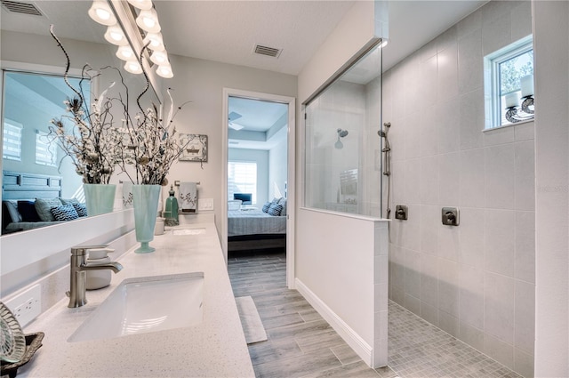 bathroom featuring vanity, a healthy amount of sunlight, and tiled shower