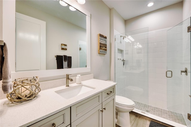 bathroom with hardwood / wood-style flooring, vanity, a shower with shower door, and toilet