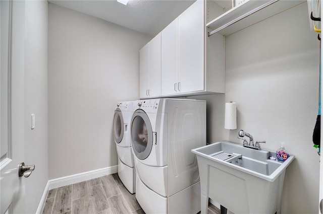 washroom featuring cabinets, washing machine and dryer, and sink