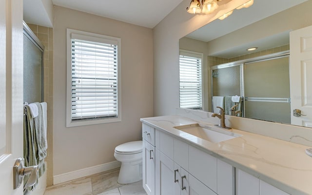 bathroom featuring vanity, toilet, and a shower with door