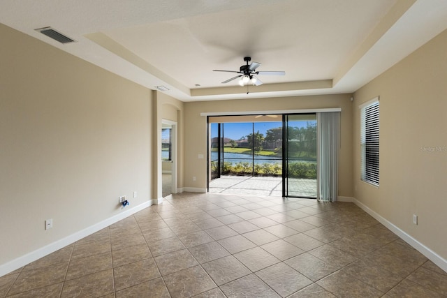 unfurnished room featuring light tile patterned floors, ceiling fan, and a tray ceiling