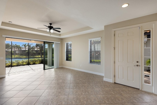 spare room with ceiling fan and a tray ceiling