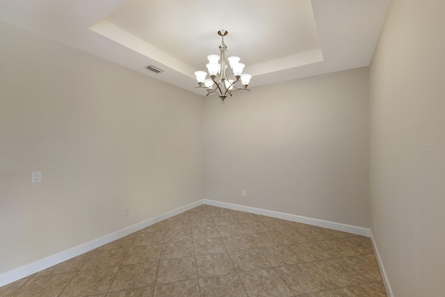 spare room featuring a notable chandelier and a raised ceiling