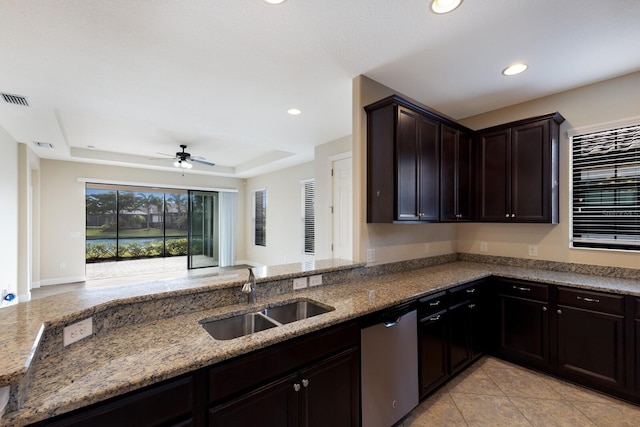 kitchen with sink, dishwasher, light stone counters, a raised ceiling, and ceiling fan