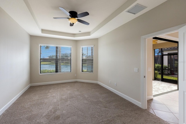 spare room with ceiling fan, light carpet, and a tray ceiling