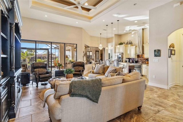 living room with a high ceiling, ceiling fan, and crown molding