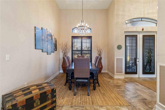 dining space with french doors, a towering ceiling, and a notable chandelier