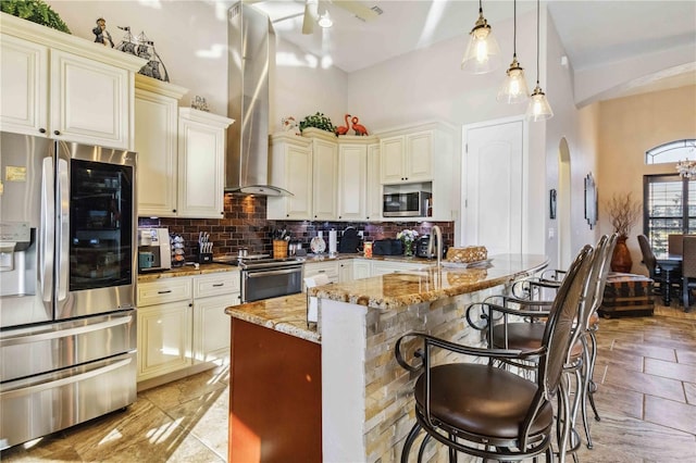 kitchen with decorative backsplash, appliances with stainless steel finishes, light stone counters, decorative light fixtures, and cream cabinetry