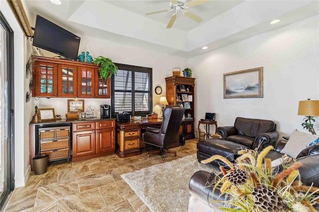 office area featuring a raised ceiling and ceiling fan