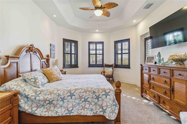 carpeted bedroom with a tray ceiling and ceiling fan